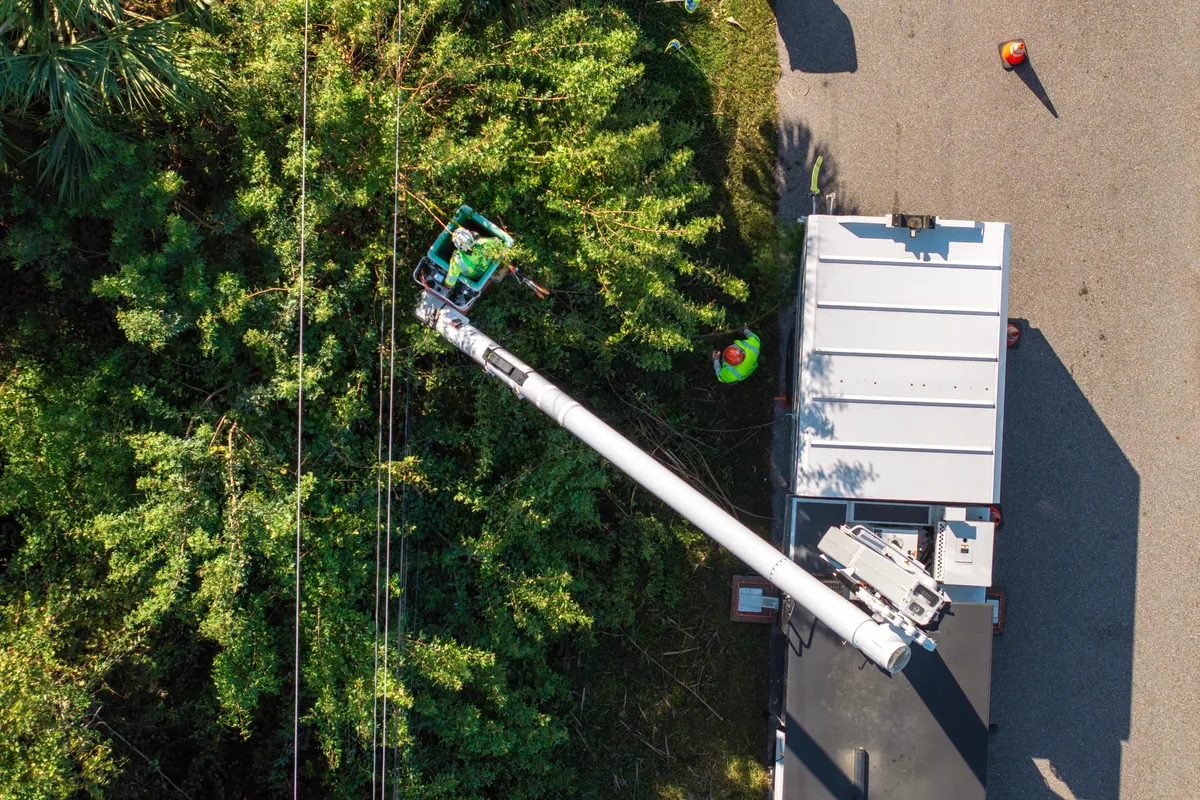 Aerial view of bucket truck trimming trees on residential street